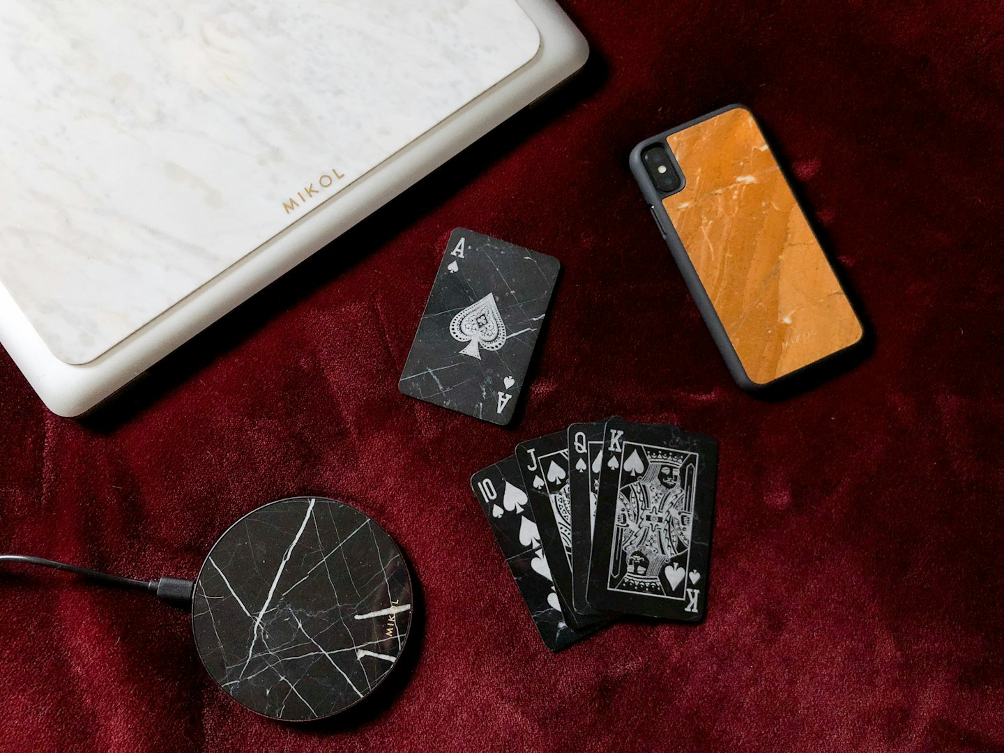 Marmorierte Technik-Accessoires und Spielkarten auf rotem Samt.