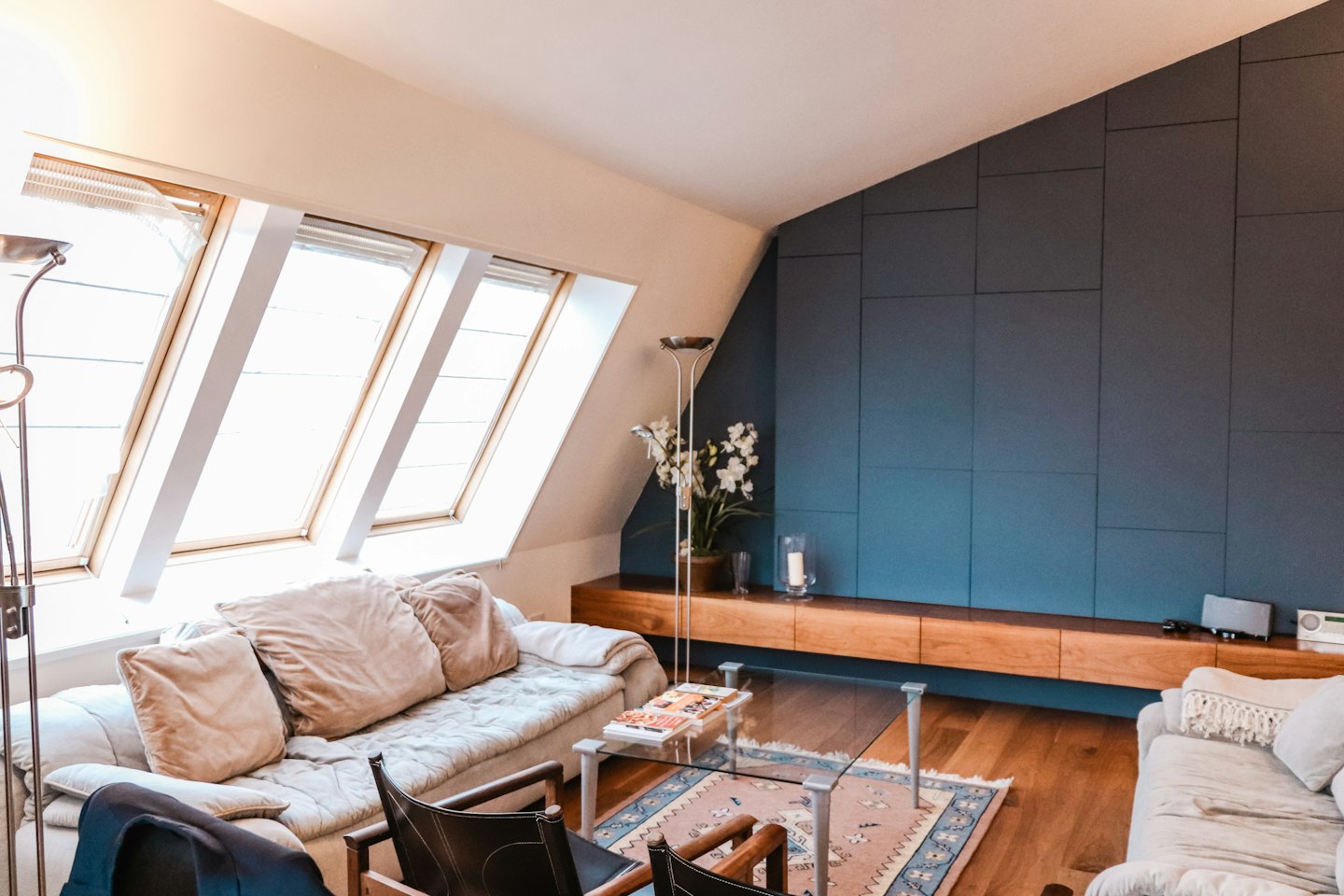 Modernes Wohnzimmer mit blauer Akzentwand und Dachfenstern.